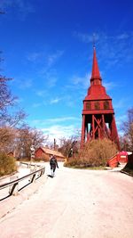 Scenic view of tourist walking towards museum against cloudy sky