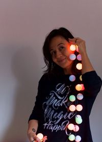 Portrait of smiling woman standing against wall