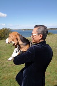 Side view of man with dog standing on field