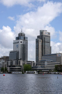 Buildings by river against sky in city