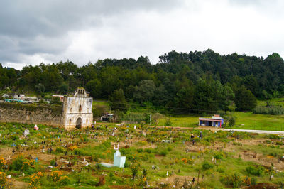 Built structure on field by trees against sky