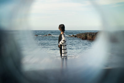 Man standing in sea against sky