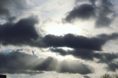 Low angle view of sunlight streaming through clouds