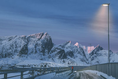 Road by snowcapped mountains against sky during winter