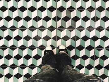 Low section of man standing on patterned tiled floor