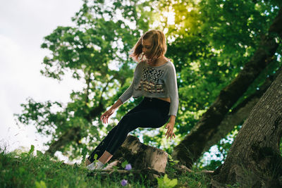 Young woman sitting on tree