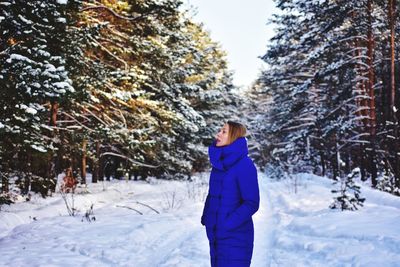Woman looking up while standing on snowy land