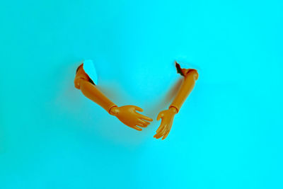 Close-up of figurine hand coming out from blue background