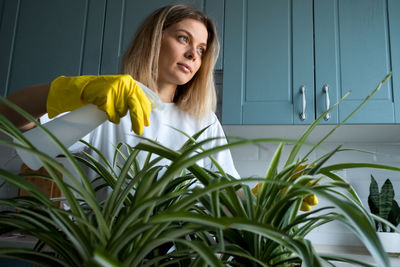 Woman gardening takes care house plants at kitchen