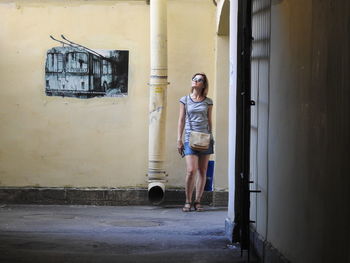 Full length of woman standing against wall