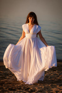 Young woman in white dress on the beach