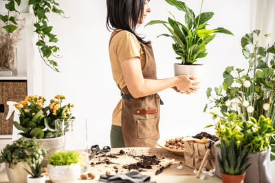 Portrait of young woman holding potted plant at home