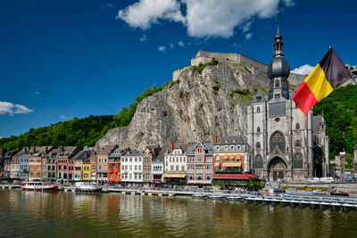 Buildings by river against sky