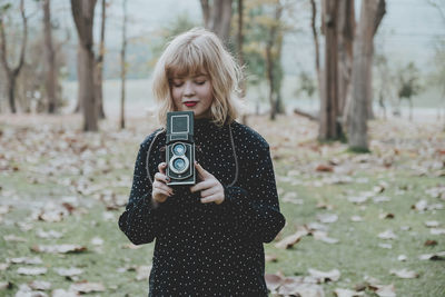 Woman holding camera in forest