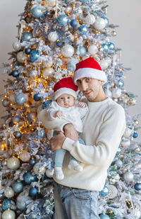 Rear view of woman standing against christmas tree