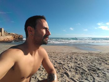 Young man on beach against sky