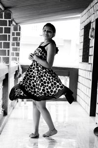 Full length portrait of a smiling young woman standing on floor