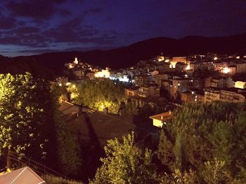 Illuminated houses in town against sky at night