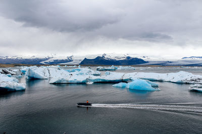 Scenic view of glacier in sea against sky