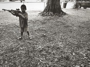 Full length of boy standing on tree trunk in field