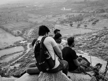 Rear view of people sitting on landscape against mountain