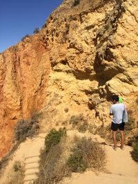 Rear view of male hiker standing on mountain during sunny day