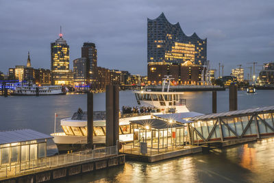 Germany, hamburg, ferry docked in hafencity at dusk with elbphilharmonie in background