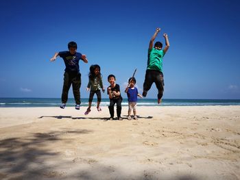 Siblings at beach against clear sky