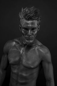 Portrait of shirtless man against black background