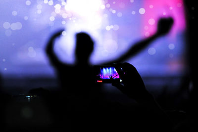 Man photographing illuminated smart phone at music concert