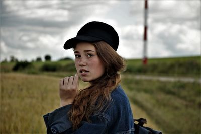 Portrait of young woman while standing on field