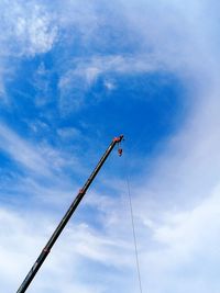 Low angle view of crane against cloudy sky