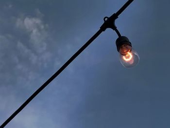 Low angle view of illuminated light bulb against sky