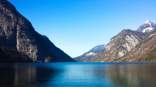 Scenic view of lake and mountains against clear blue sky