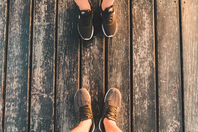 Low section of friends standing on wooden floor