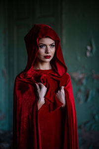 Portrait of beautiful young woman standing against red wall