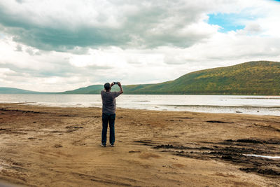 A tourist at lake nakuru taking photos with a mobile phone in lake nakuru national park in kenya