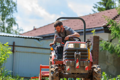 A man on a mini-excavator levels a piece of land, loosens the soil.