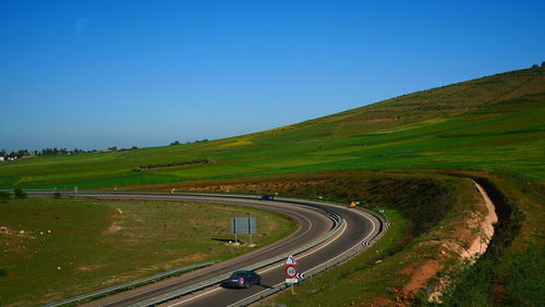 Aerial view of winding road against clear blue sky