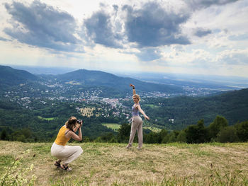 Woman photographing friend on mountain