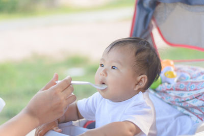 Cropped hand of mother feeding baby in stroller