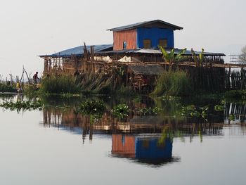 House on lake by building against sky