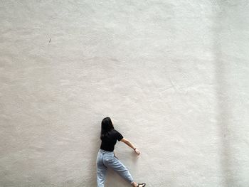 Rear view of woman standing against wall