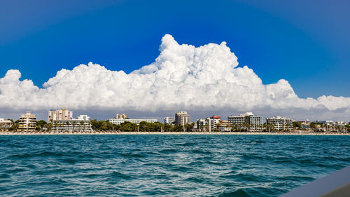 Sea by buildings against blue sky