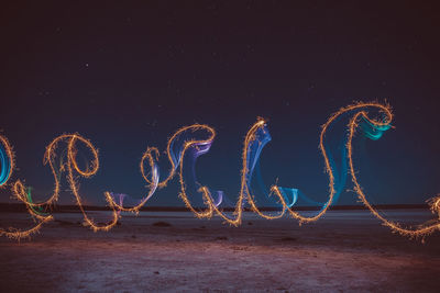 Firework display on beach against sky at night