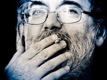 Close-up portrait of man wearing eyeglasses against black background