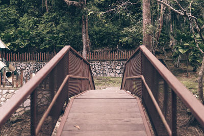 Wooden footbridge amidst trees in forest