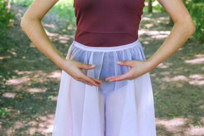 Midsection of woman doing ballet dance on field