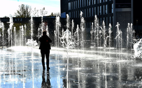 Rear view of silhouette man walking by fountain