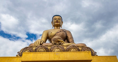 Low angle view of buddha statue against sky